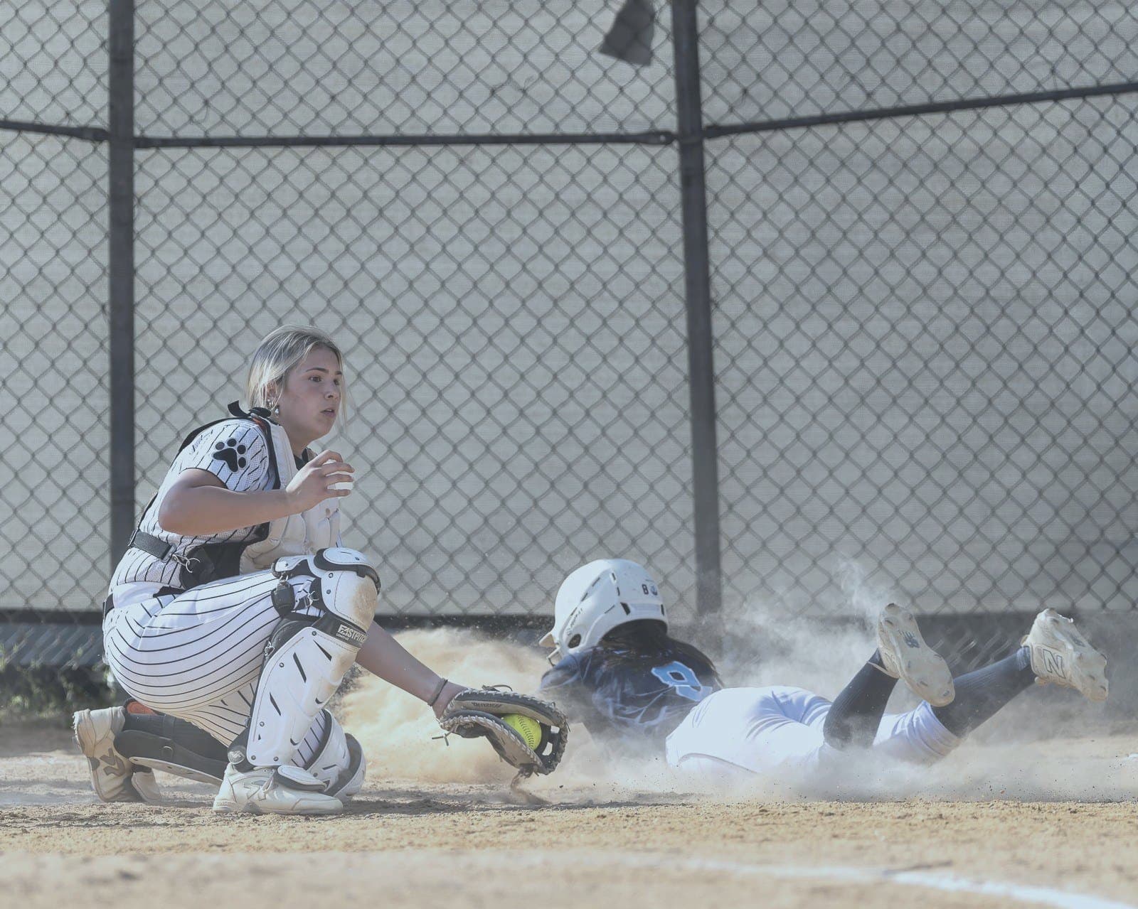Runner slides into home plate in a cloud of dust