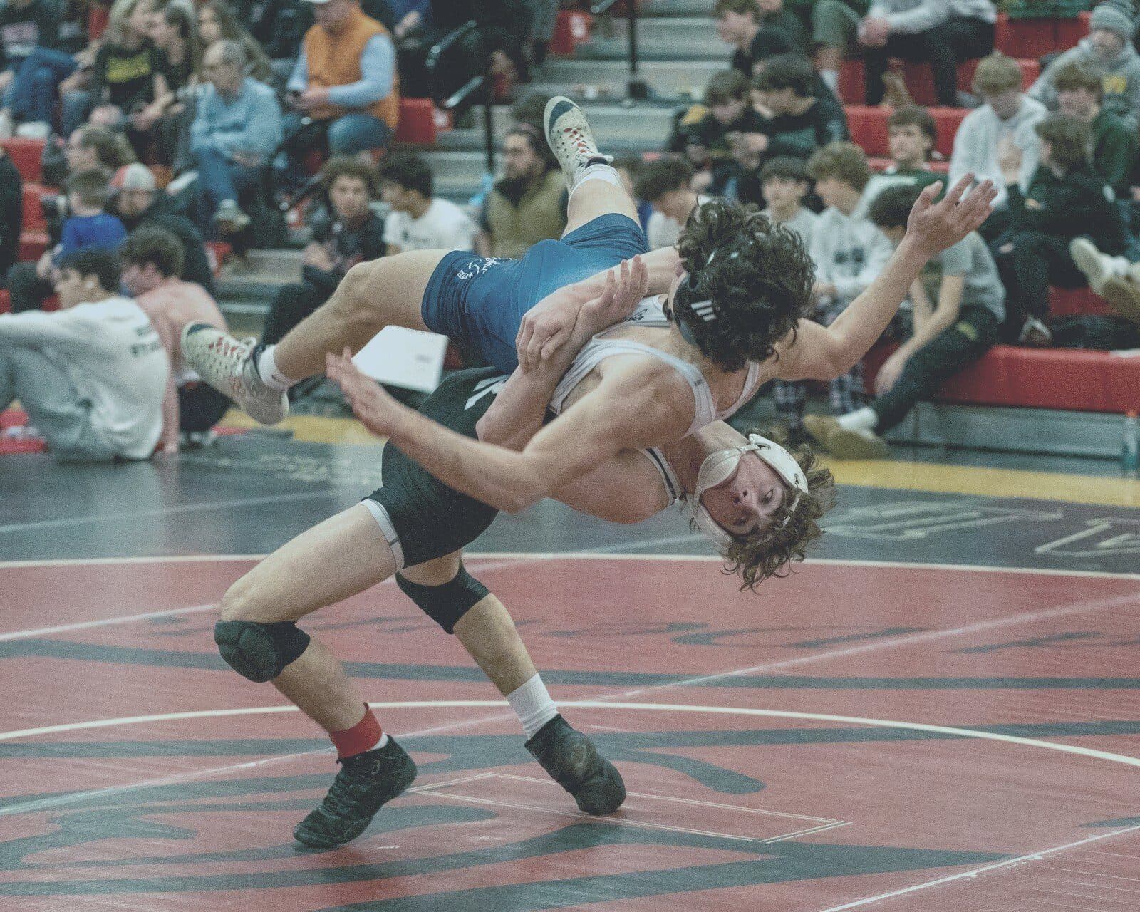 Wrestler executes suplex in front of packed crowd